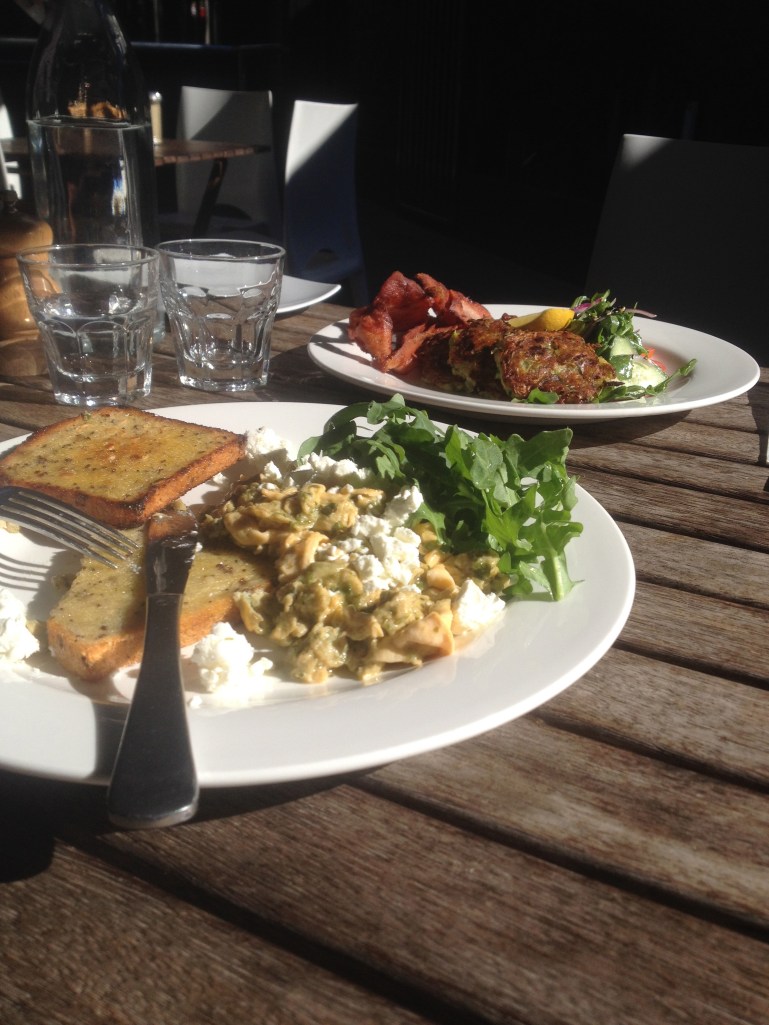 Green scrambled eggs in the foreground ($16 I think), zucchini fritters in the back ground ($16.50) with a side of bacon ($4)